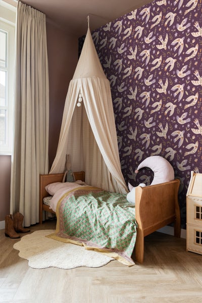 Kinderzimmer mit Holzbett, Baldachin, gemusterter Tapete und Teppich