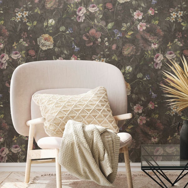 Szene mit floraler Tapete, Sessel mit Kissen und Decke sowie Beistelltisch