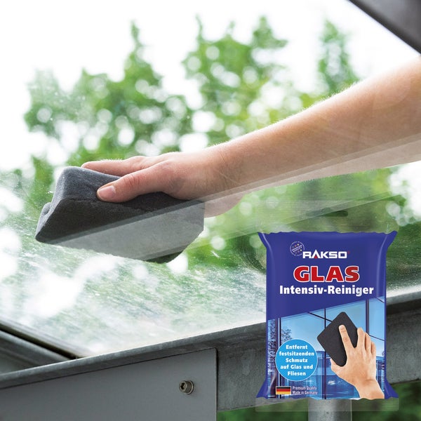 Reinigung einer Glasfläche mit dem Rakso Glas Intensiv-Reiniger Schwamm, Verpackung im Vordergrund sichtbar.