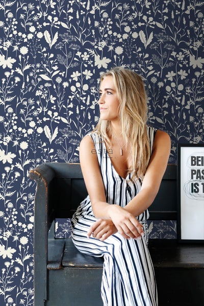 Szene mit einer Frau vor einer floralen Tapete auf einer Bank sitzend
