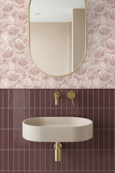 Badezimmer mit Blumen-Tapete, ovalem Spiegel, hängendem Waschbecken und Wandarmatur in einem modernen, eleganten Design.