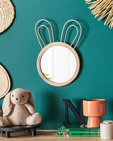 Dekorative Szene mit Spiegel im Hasendesign, Stoffhase, Pflanzgefäß und Dekoration