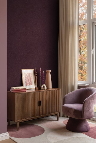 Einrichtungsbeispiel eines Wohnzimmers mit gemusterter Tapete, Holzkommode, Dekorationen und einem Sessel