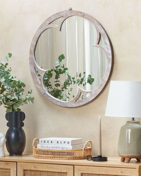 Dekoratives Interieur mit rundem Spiegel, Tischlampe und Dekoration auf einem Holzschrank