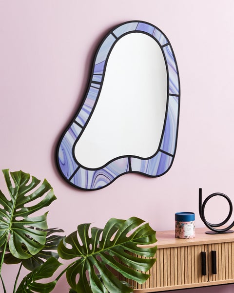 Dekorativer Wandspiegel mit blauem Rahmen, Monstera Pflanze und Dekoration auf einem Schrank