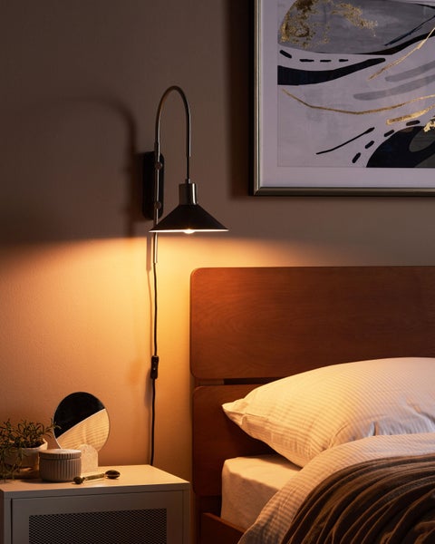 Schlafzimmer mit Bett, Nachttisch und Wandleuchte