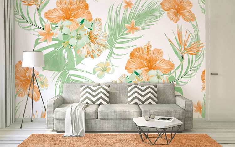 Fototapete mit tropischem Muster aus Hibiskusblüten und Palmblättern in einem hellen Wohnzimmer hinter einem grauen Sofa.