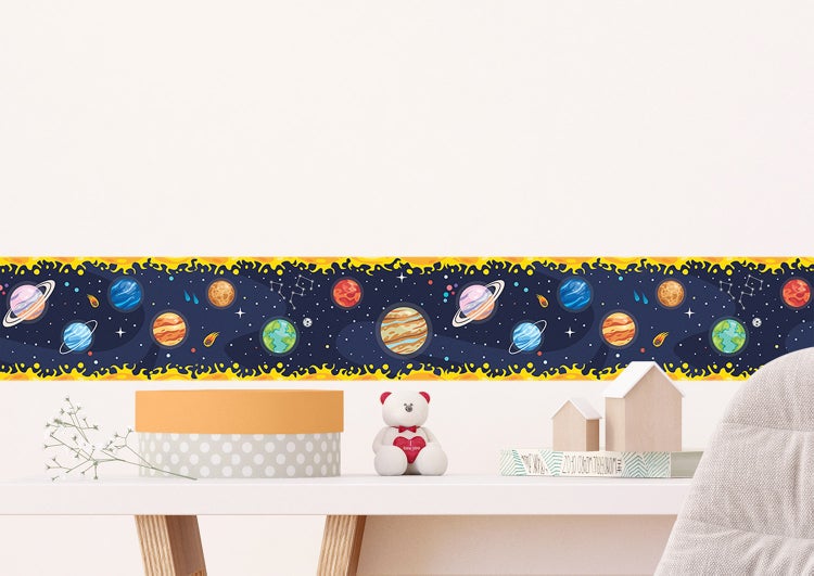 Tapetenbordüre mit Weltraum-Motiv, Planeten und Sternen in einem hellen Kinderzimmer über einem Bett.