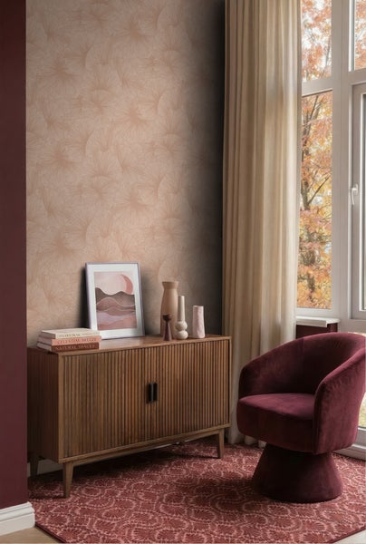 Wohnraum mit Blättermustertapete, Sideboard aus Holz, Sessel mit Textilbezug und gemustertem Teppich vor einem Fenster.