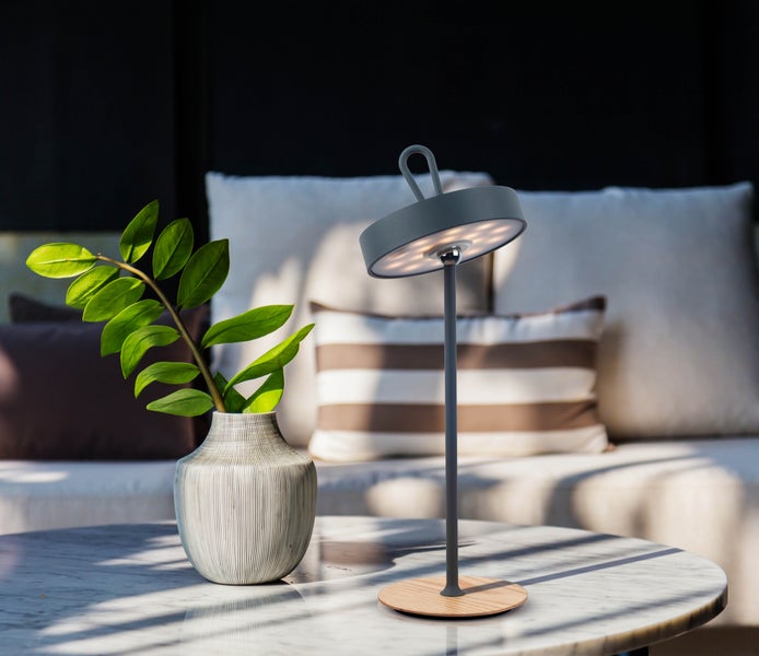 Dekorative Tischleuchte mit Pflanzenarrangement auf einem Tisch