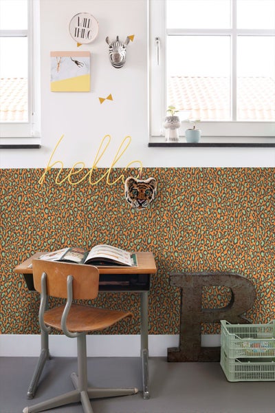 Vliestapete mit Leopardenmuster in einem hellen Kinderzimmer mit Holzschreibtisch, Stuhl und Wanddekoration.