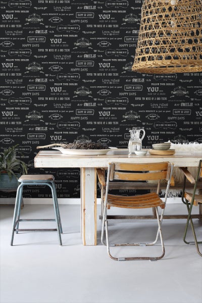 Esstisch-Szene mit dekorativer Schriftzug-Tapete, Pendelleuchte und Vintage-Stühlen für eine helle und freundliche Atmosphäre