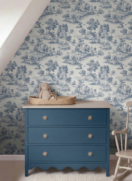 Tapete mit Toile-de-Jouy-Muster in einem hellen Zimmer mit blauer Kommode und Schaukelstuhl.