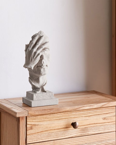 Dekofigur Gesicht mit Hand auf einem Nachttisch