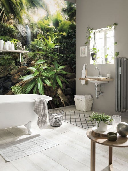 Badezimmer mit Badewanne, Waschtisch, Heizkörper und Fototapete mit Dschungelmotiv