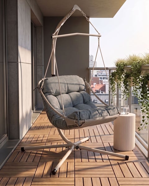 Hängesessel mit gepolstertem Sitz und Metallgestell auf einem modernen Balkon mit Holzboden und Geländer.