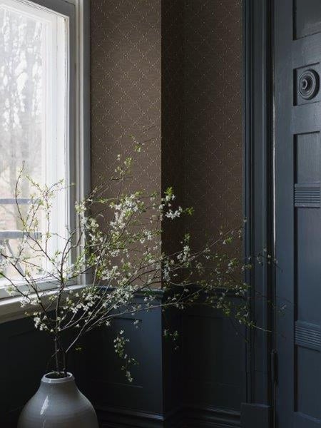 Innenraum mit Fenster, dekorativer Vase mit Zweigen und gemusterter Tapete