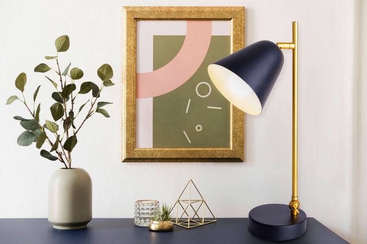 Dekorative Szene mit Tischleuchte, Bilderrahmen, Vase und Ziergegenständen auf einer Ablagefläche