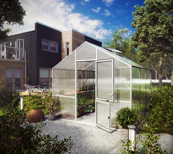 Modernes Gewächshaus mit weißem Aluminiumrahmen und Hohlkammerplatten im Garten neben einem Haus, Innenraum mit Regalen und Pflanzen.
