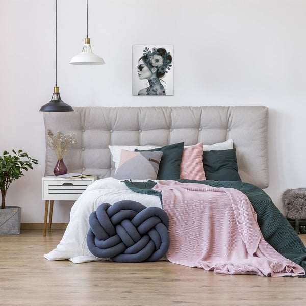 Schlafzimmer mit Bett, Kissen und einem Bild mit Blumenmotiv