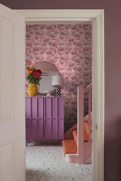 Dekorative Szene mit Kommode, Spiegel, Treppe und floraler Tapete.