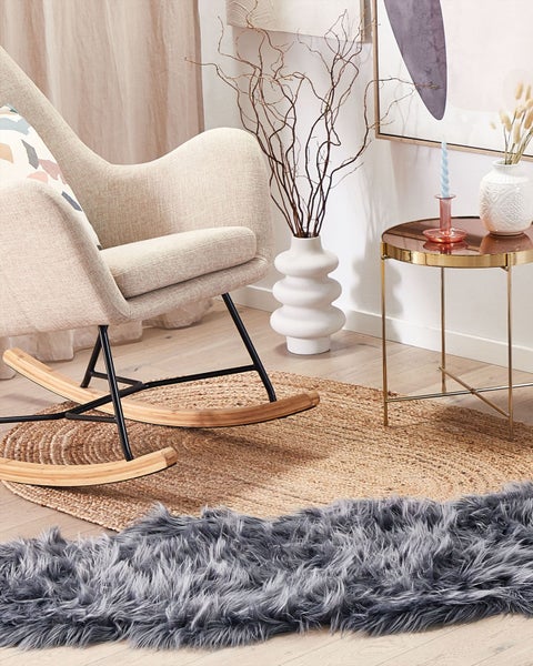 Szene mit Schaukelstuhl, Beistelltisch und Teppichen auf einem Holzboden.