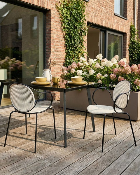Terrasse mit Tisch, Stühlen, Geschirr und Blumenkasten vor Backsteinhaus