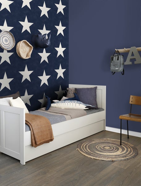 Kinderzimmer mit weißem Bett, rundem Teppich und Wanddekoration