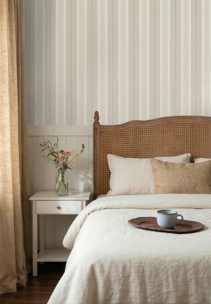 Gestreifte Tapete im Schlafzimmer über weißer Holzvertäfelung neben einem Bett mit Rattan-Kopfteil und weißem Nachttisch.