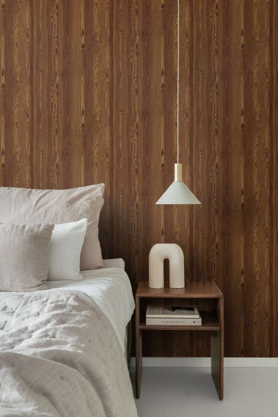 Schlafzimmer mit Vliestapete in Holzoptik im Bereich des Bettes, moderne Pendelleuchte und Nachttisch aus Holz.