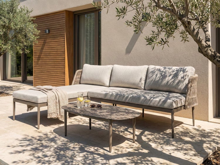 Outdoor-Szene mit Ecksofa, Couchtisch, Getränken und Dekoration auf einer Terrasse.