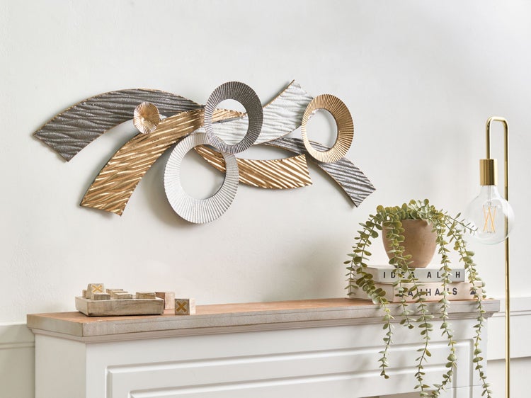Modernes Wandobjekt aus Metall mit geschwungenen Formen und Kreisen in einem hellen, organisierten Raum über einem Sideboard.