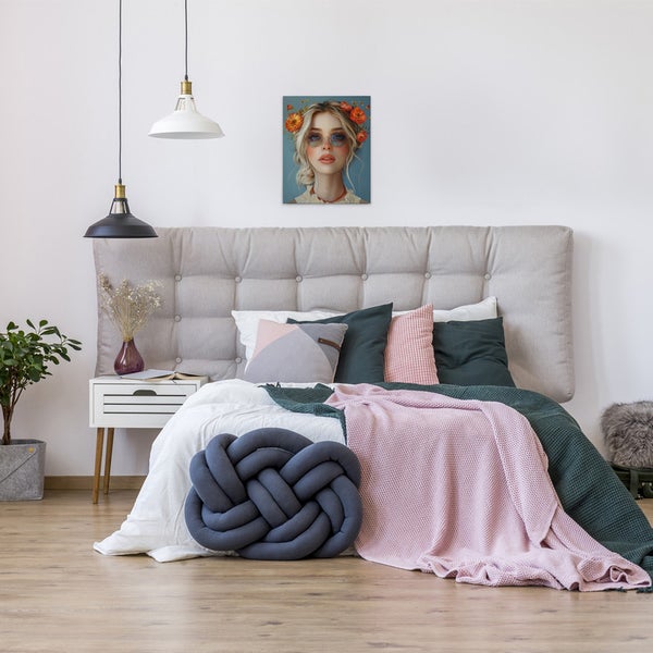 Schlafzimmer mit Bett, Nachttisch, Lampe und gerahmtem Porträt einer Frau mit Blumen