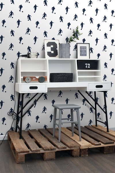 Schreibtisch mit Regalen und Stuhl auf Paletten vor einer Tapete mit Fußballmotiven