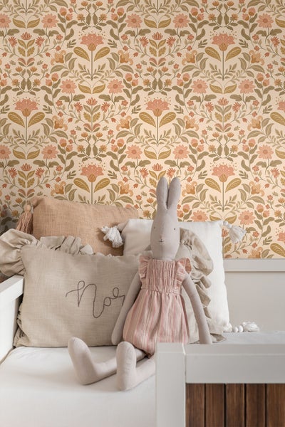 Dekorative Tapete mit Blumenmuster, kombiniert mit Kissen und einem Stoffhasen auf einem Bett.