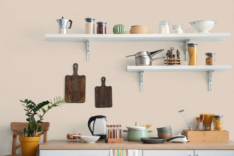 Helle, organisierte Küchenszene mit weißen Wandregalen, Vorratsgläsern, hölzernen Schneidebrettern und Küchenutensilien auf einer Arbeitsplatte.