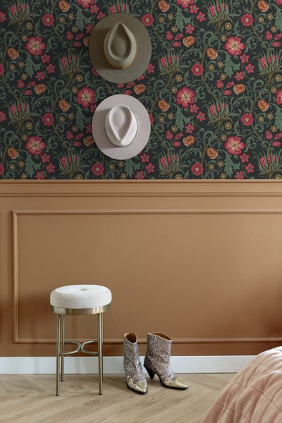 Schlafzimmer mit floraler Mustertapete, gepolstertem Bettkopfteil, Bettwäsche, strukturierter Tagesdecke und Nachttischlampe.