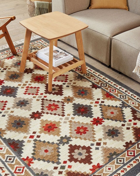Dekorativer Teppich mit geometrischen Mustern unter einem Holztisch