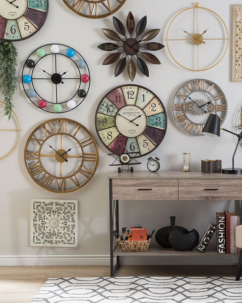 Wanddekoration mit verschiedenen Wanduhren über einem Konsolentisch mit Dekorationen