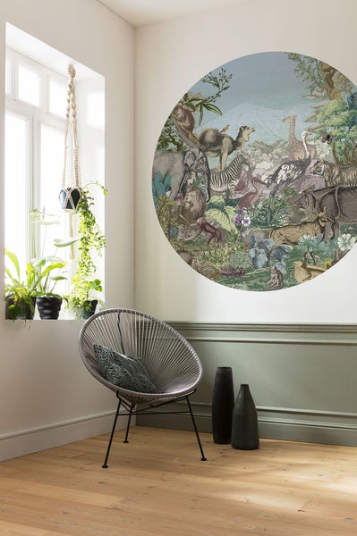 Wohnzimmer mit runder Tiermotiv-Tapete, Stuhl, Vasen und Topfpflanzen am Fenster