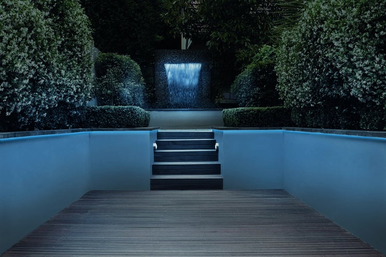 Garten mit Wasserfall, Pflanzen und Holzterrasse