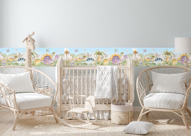 Tapetenbordüre mit Dinosaurier-Motiv in einem hellen Kinderzimmer mit Babybett aus Holz, Rattansesseln und Schaukelpferd.