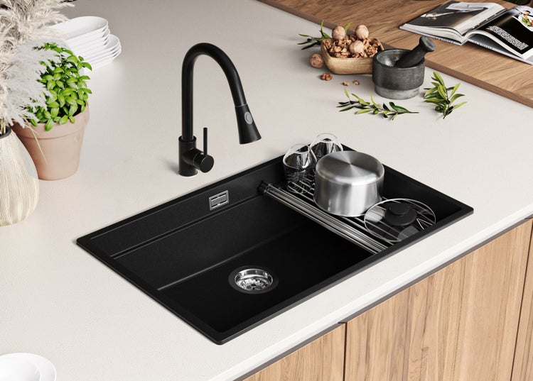 Schwarze Küchenspüle mit Wasserhahn und Abtropfgestell auf einer Arbeitsplatte.
