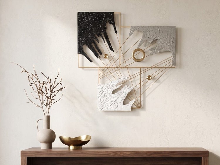 Moderne abstrakte Wanddekoration aus Metall mit geometrischen Formen und strukturierter Oberfläche über einer Anrichte mit Vase und Schale.