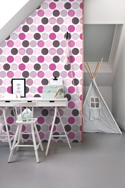 Dekoriertes Kinderzimmer mit Schreibtisch, Stuhl und Zelt vor einer Wand mit Punktmuster