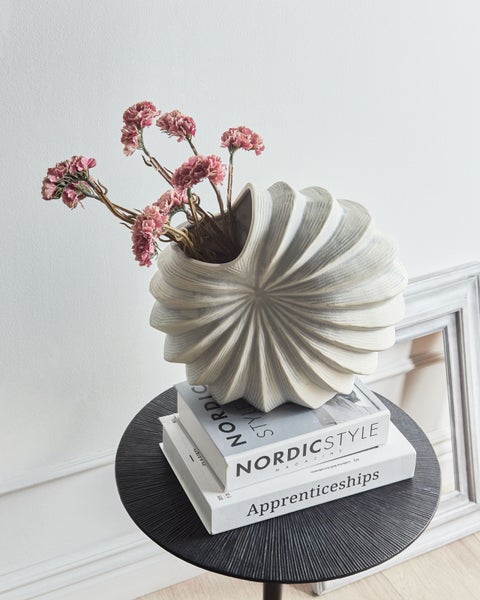 Dekorative Szene mit einer geriffelten Vase, Blumen und Büchern auf einem Beistelltisch