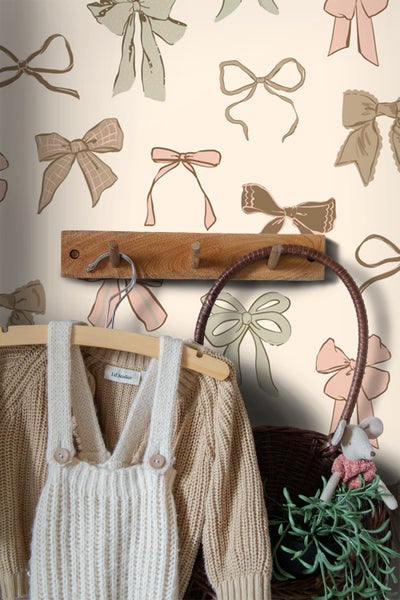 Szene mit Kinderkleidung an einer Holzgarderobe vor einer Wand mit Schleifenmuster