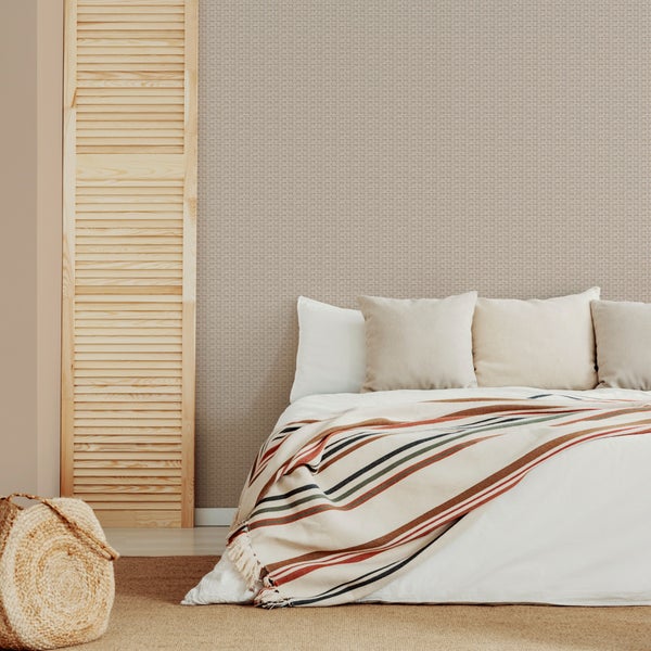 Schlafzimmer mit strukturierter Tapete in Weboptik, Holztür mit Lamellen und Bett mit gestreiftem Überwurf.