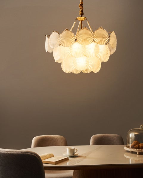 Eine moderne Esszene mit einem Tisch, Stühlen und einer Hängelampe mit Muscheldekor.
