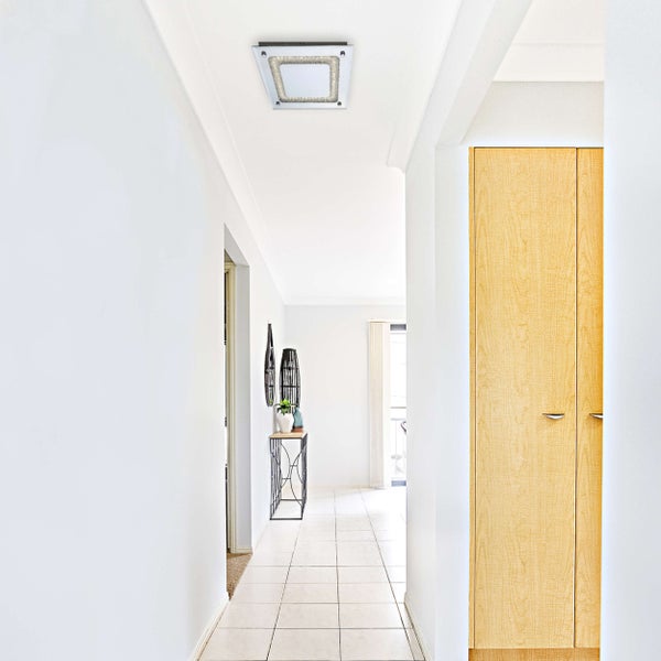 Heller Flur mit Deckenleuchte, Holzschrank und Dekoration
